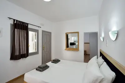 a white bedroom with two beds and a mirror at Urban Studios Manos in Chania Town