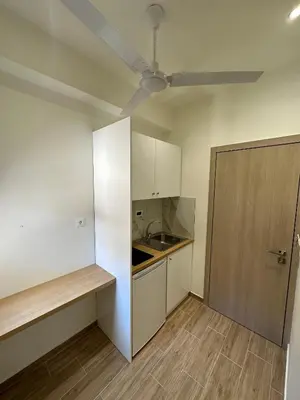 a small kitchen with white cabinets and a door at Lissos Rooms Sougia in Sougia
