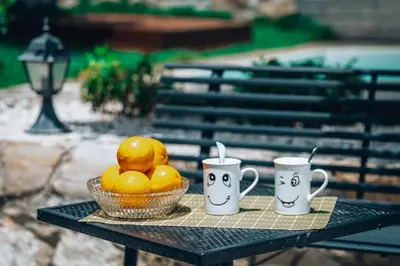 a table with a bowl of oranges and two mugs at Villa Stafidaki in Stalos