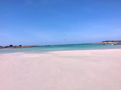 a beach with a person flying a kite in the ocean at VILLA ASTERAKI private pool, magic sunsets, near Elafonisi in Ãyios FÃ³tios