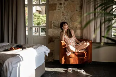 a woman sitting in a chair next to a window at Divino Suites Chania in Chania Town