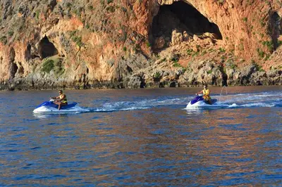 two people are riding on canoes in the water at Raph's Studios-Apts By The Sea in Agia Marina Nea Kydonias