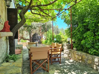 a patio with a table and chairs under a tree at Wood & Stone in Kissamos