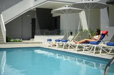 a woman sitting in lawn chairs next to a swimming pool at Athina Suites Luxury Suites Near The Sea Platanias in Plataniás