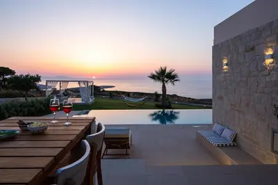 a patio with a table with two glasses of wine at Elias Luxury Villa in Kalathas