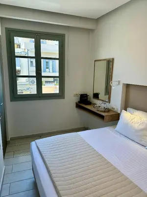 a bedroom with a bed with a mirror and a window at Cretan Berry Portou in Chania Town