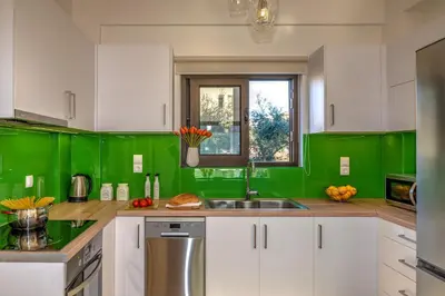 a green kitchen with white cabinets and a sink at Platanias Villa Mirsini in Plataniás