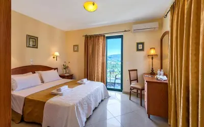 a hotel room with a bed and a desk and a window at Antilia Apartments in Tavronitis