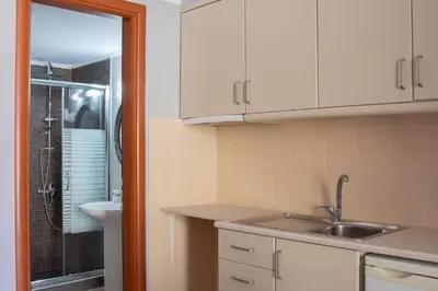 a kitchen with white cabinets and a sink and a shower at Narkissos 'SUPERB' in Chania Town