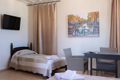a room with a bed and a desk and a painting at Narkissos 'SUPERB' in Chania Town