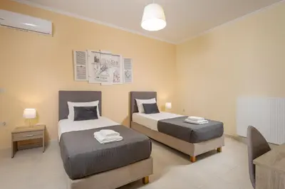 a bedroom with two beds and a couch and a table at NeSo - Peter's Flat steps to Beach with Great Views in Kolymvari