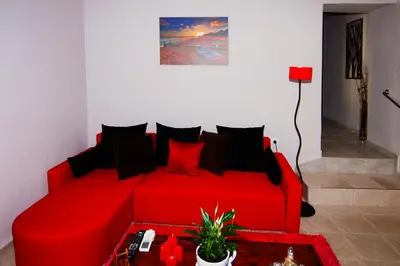 a red couch with black pillows in a living room at Maria's house in front of the beach in Chania Town