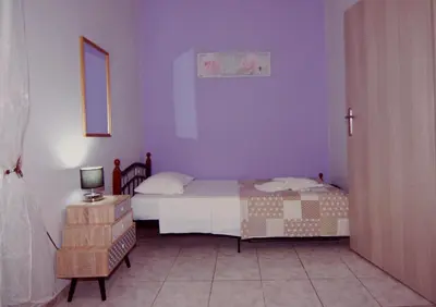 a bedroom with a bed with purple walls and a table at Maria's house in front of the beach in Chania Town