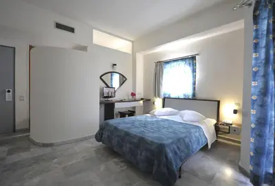 a bedroom with a bed and a window and a desk at Rodon Hotel in Chania Town