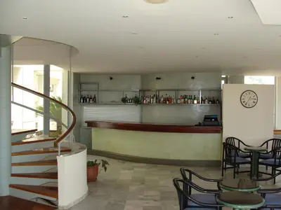 a restaurant with a bar with chairs and a clock on the wall at Rodon Hotel in Chania Town