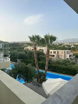 a view of a swimming pool with palm trees and buildings at Rodon Hotel in Chania Town