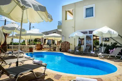 a pool with chairs and umbrellas next to a building at Irinoula Dreams in Kolymvari