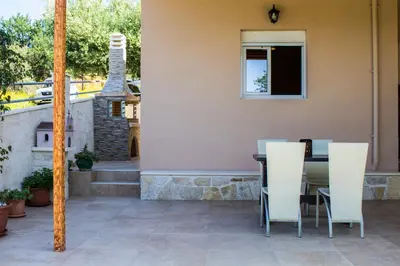 a patio with a table and white chairs at Lydia's Apartment in Stílos