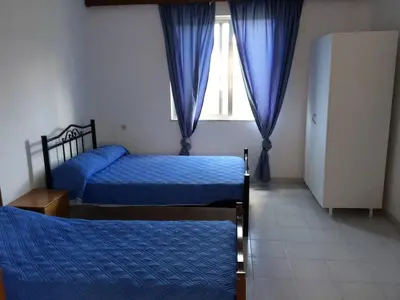 a bedroom with two beds and a window with blue curtains at House with Sea View close to Platanias in Vrísai