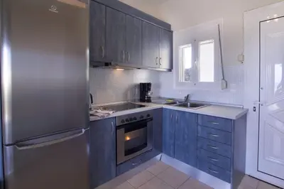 a kitchen with blue cabinets and a stainless steel refrigerator at Like Home in Agia Marina Nea Kydonias