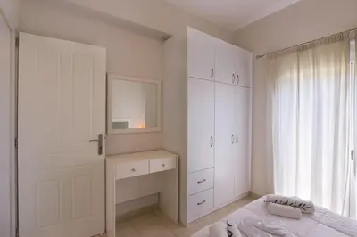 a bedroom with white cabinets and a bed and a mirror at Like Home in Agia Marina Nea Kydonias