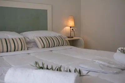 a white bed with two pillows and a table with a lamp at Like Home in Agia Marina Nea Kydonias