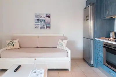 a small kitchen with a white couch and a refrigerator at Like Home in Agia Marina Nea Kydonias
