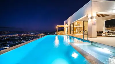 a pool with a view of a city at night at Villa Con Vista- Heated Pool 4 bdr sleeps 8 in Tsikalariá