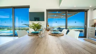 a dining room with a large wooden table and white chairs at Villa Con Vista- Heated Pool 4 bdr sleeps 8 in Tsikalariá