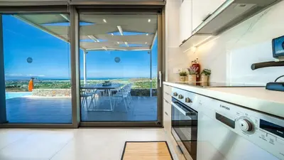 an open kitchen with a view of a dining table at Villa Con Vista- Heated Pool 4 bdr sleeps 8 in Tsikalariá