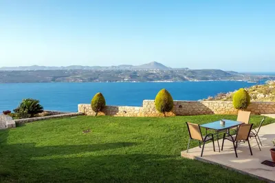 a table and chairs on a lawn with a view of the water at Margarita Apt - Amazing Relaxing View in Megála Khoráfia