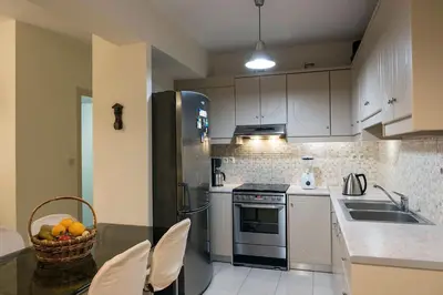 a kitchen with white cabinets and a basket of fruit on a table at Margarita Apt - Amazing Relaxing View in Megála Khoráfia