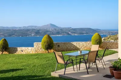 a table and chairs on a patio with a view of the water at Margarita Apt - Amazing Relaxing View in Megála Khoráfia