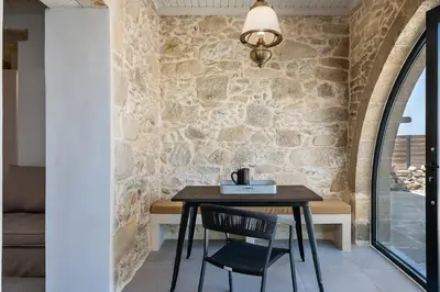 a table and chair in a room with a stone wall at Trialonia Luxury Villa in Kissamos