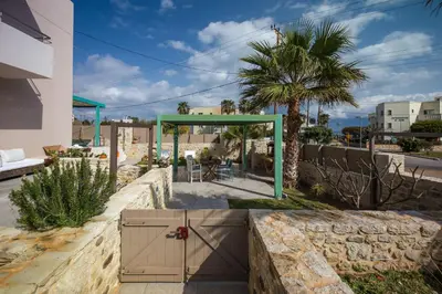 a building with a gate and a palm tree at Arodamos Studios & Apts in Kissamos