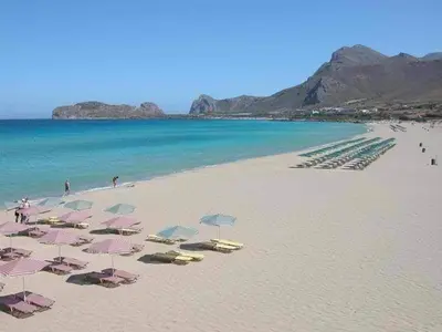 a beach with a bunch of umbrellas and the ocean at Terra Falasarna in Falasarna