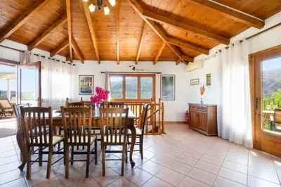 a dining room with a wooden ceiling and a table and chairs at 4-bedroom Topolia House in Topólia