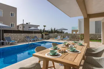 a patio with a table and chairs next to a pool at Villa Kambos Platanias in Plataniás