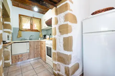 a kitchen with a stone wall and a refrigerator at Topolia 1 Bedroom Villa in Topólia