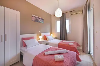 a hotel room with two beds and a window at Omega Comfy Apartments Almyrida in Almirida