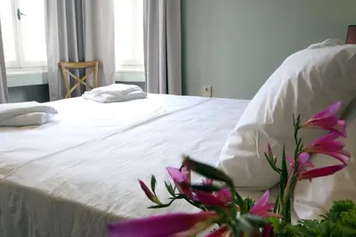 a bed with white sheets and purple flowers on it at Spacious townhouse close to Chania center in Chania Town