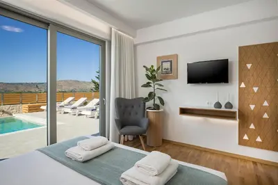 a bedroom with a bed and a tv and a balcony at Villa White Harmony in Khámbatha