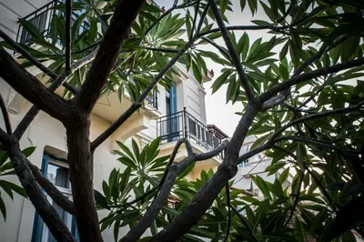 a building with a balcony seen through the trees at Creta Elena in Chania Town