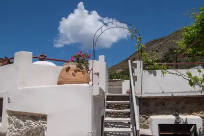 a pot on the side of a white building with stairs at Feneri- cozy Apartment 20' from Elafonisi beach in Elafonisi