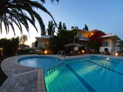 a swimming pool in front of a house at Cormoranos Apartments Rooms Eco Green in Kissamos