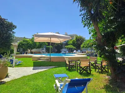 a group of chairs and an umbrella next to a pool at Cormoranos Apartments Rooms Eco Green in Kissamos