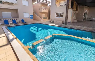 a large swimming pool with blue water in a building at Sun Beach Apartments in Kato Daratso
