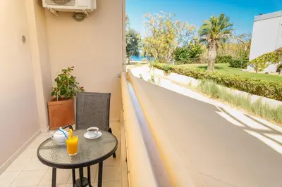 a table with a cup of orange juice on a balcony at Sun Beach Apartments in Kato Daratso