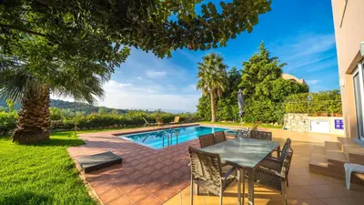 a patio with a table and chairs next to a swimming pool at Meliades Villas in Agia Marina Nea Kydonias