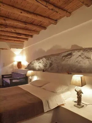 a bedroom with a large bed and a table with a lamp at Villa Niki in Loutro